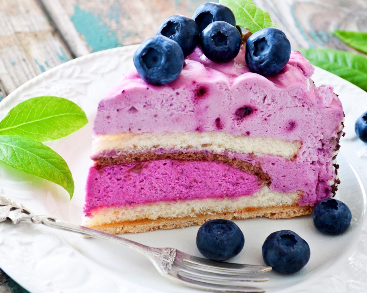 Торт с черничным муссом и свежими ягодами черники на белой тарелке 