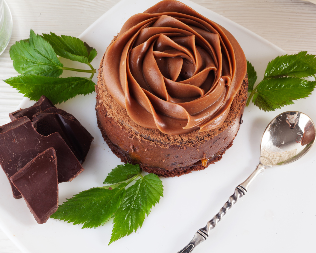 Пирожное с шоколадной кремовой розой на тарелке
