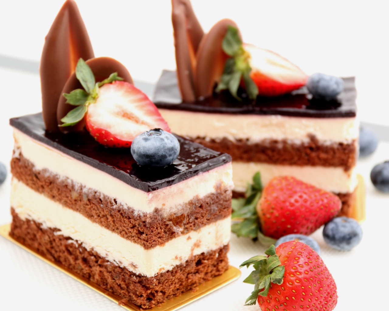 Пирожные с шоколадом, кремом и ягодами клубники и черники