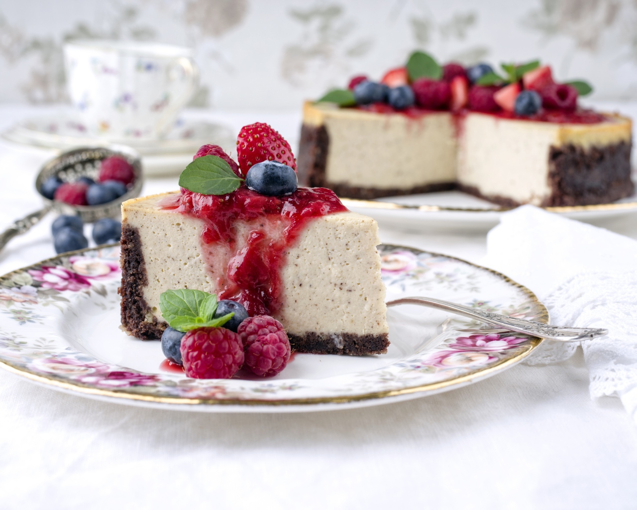 Чизкейк на столе с ягодами малины, черники и клубники