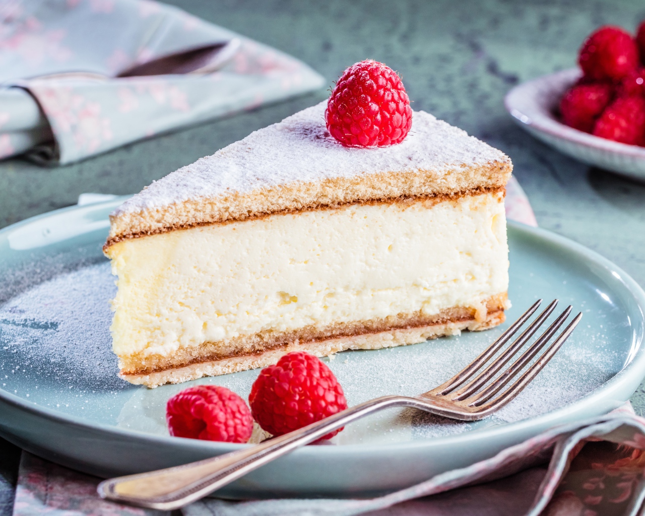 Чизкейк с сахарной пудрой и ягодами малины на тарелке