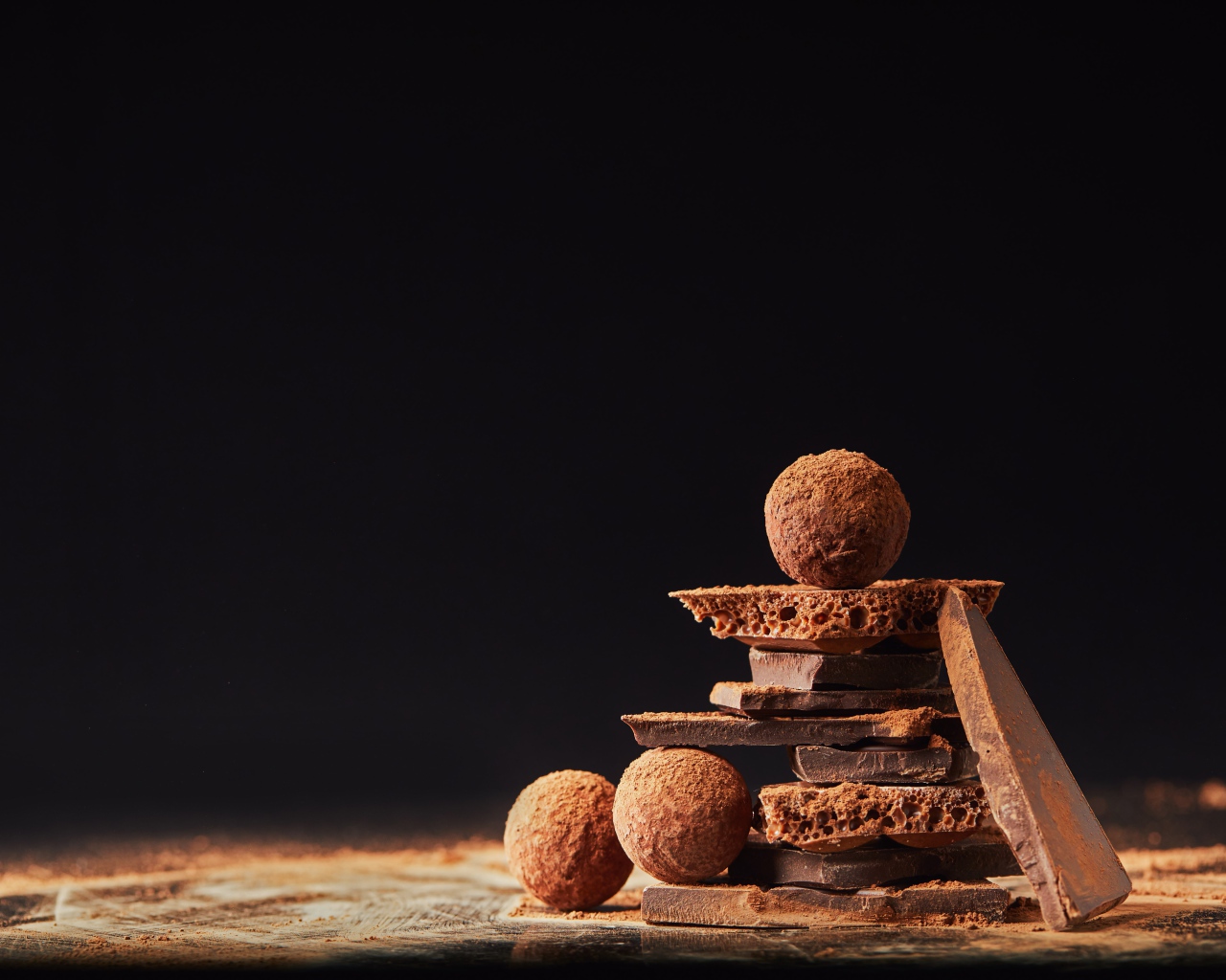 Шоколадные шарики и кусочки шоколада на черном фоне