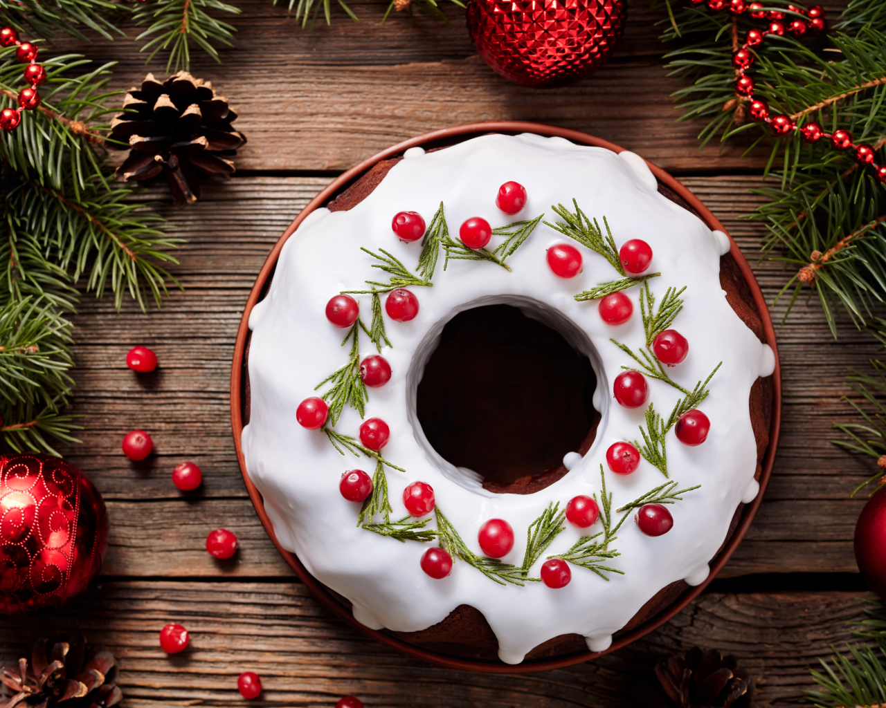 Рождественский пирог с ягодами клюквы на деревянном столе с еловыми ветками