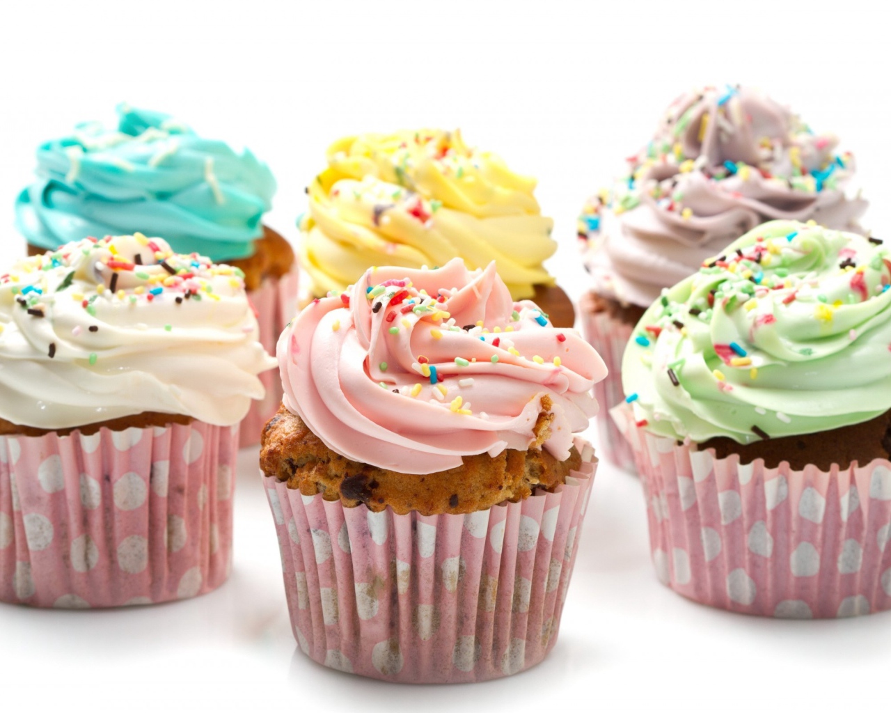 Кексы с разноцветным кремом на белом фоне