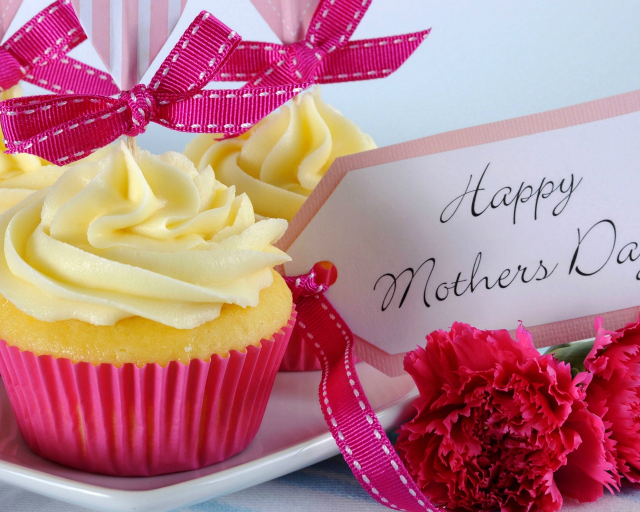 Кексы с кремом рядом с гвоздиками и пожеланиями к Дню матери
