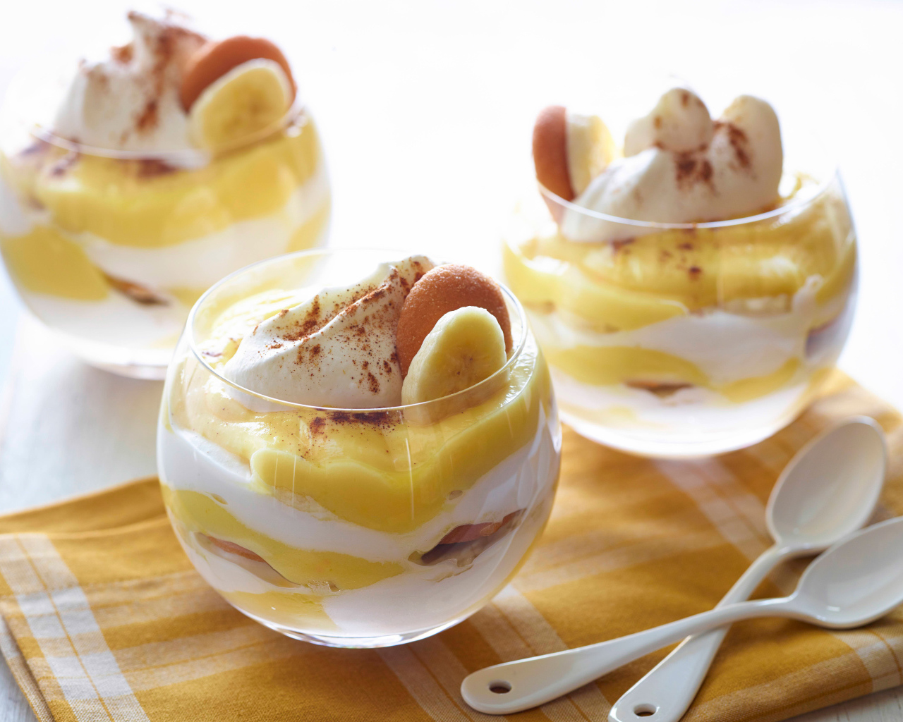 Десерт с бананами и печеньем в стаканах на столе 