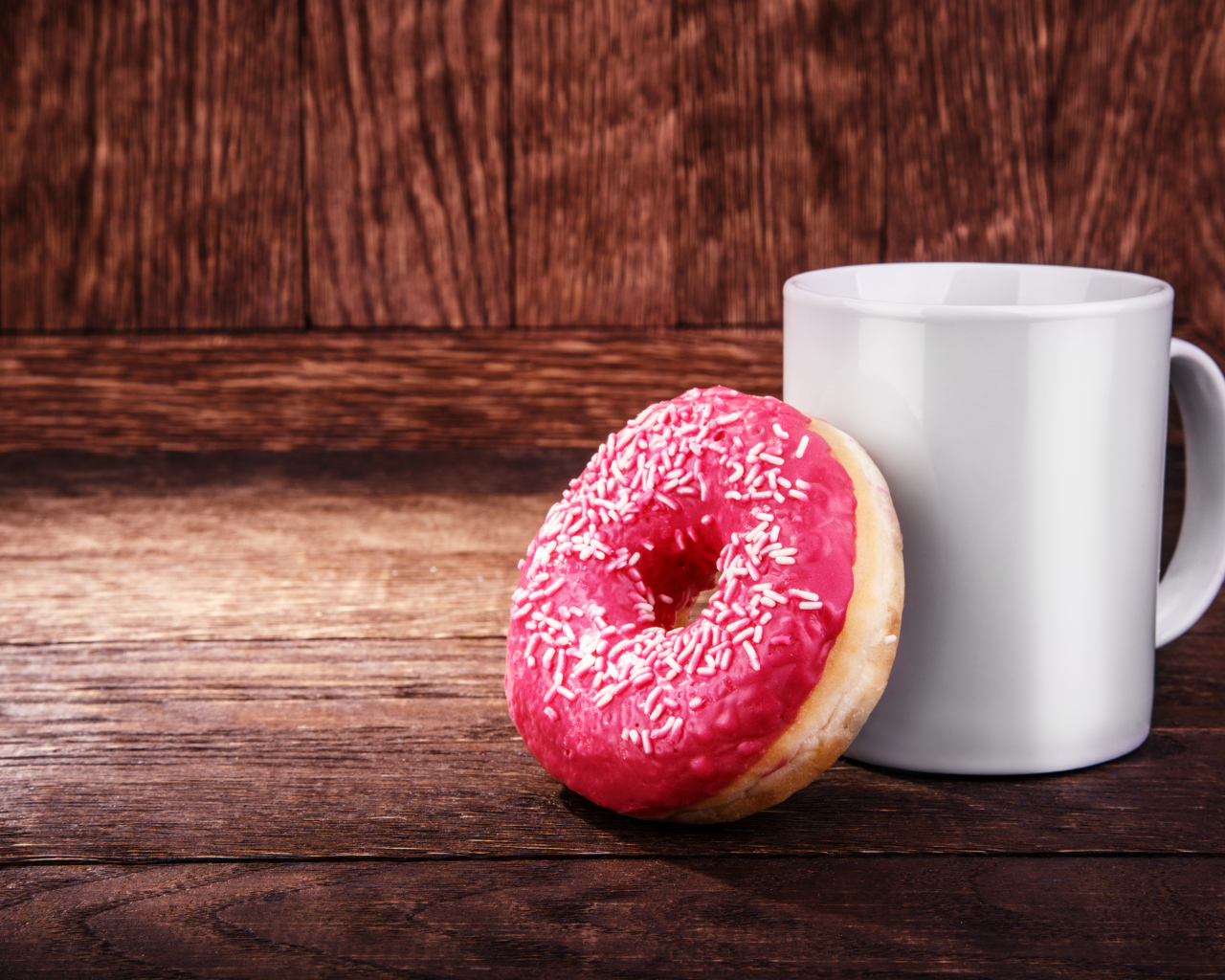 Пончик с белой кружкой на деревянном столе