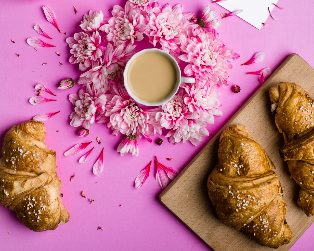 Свежие круассаны на столе с чашкой какао и цветами хризантемы
