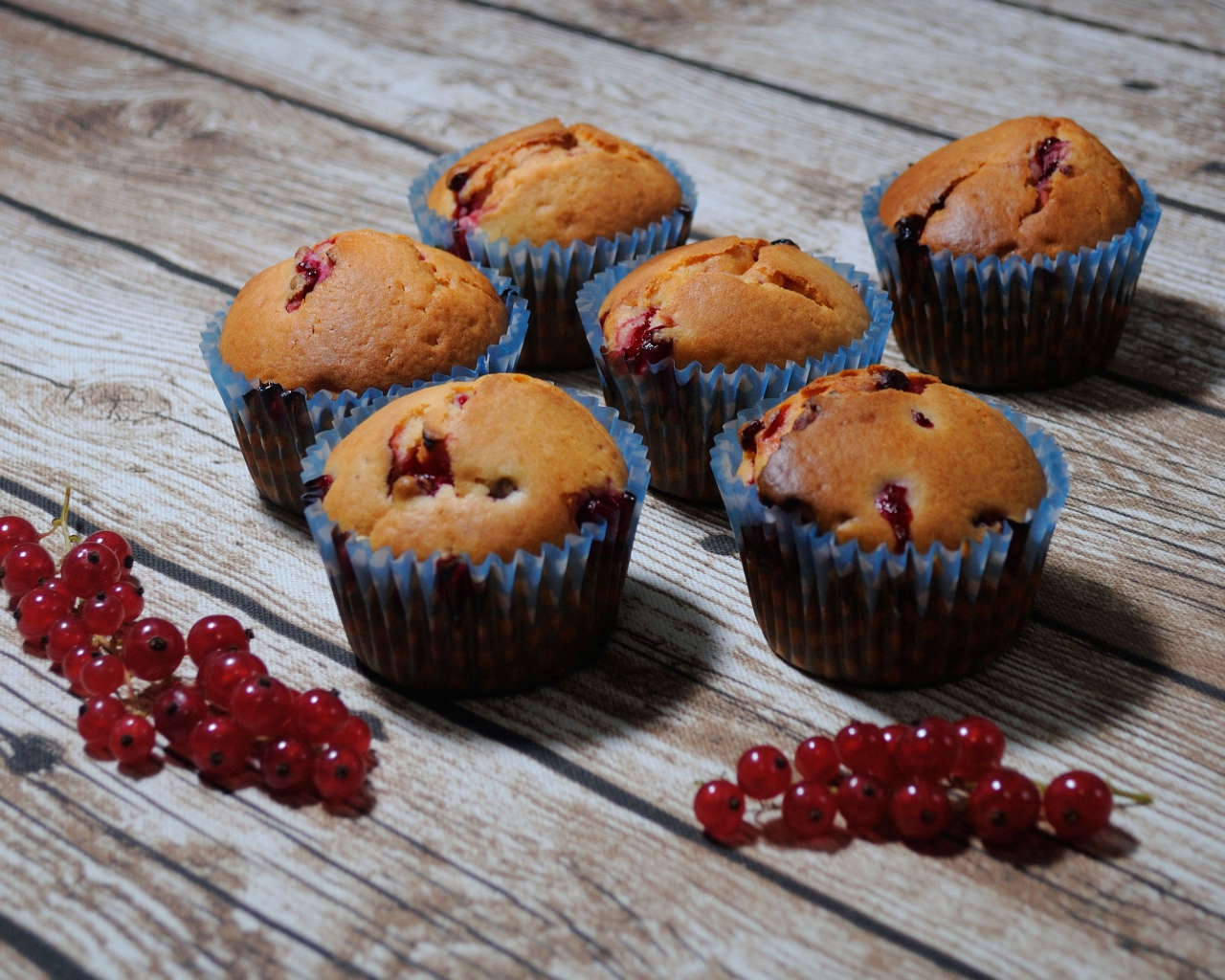 Fresh cupcakes with red currants on a wooden table