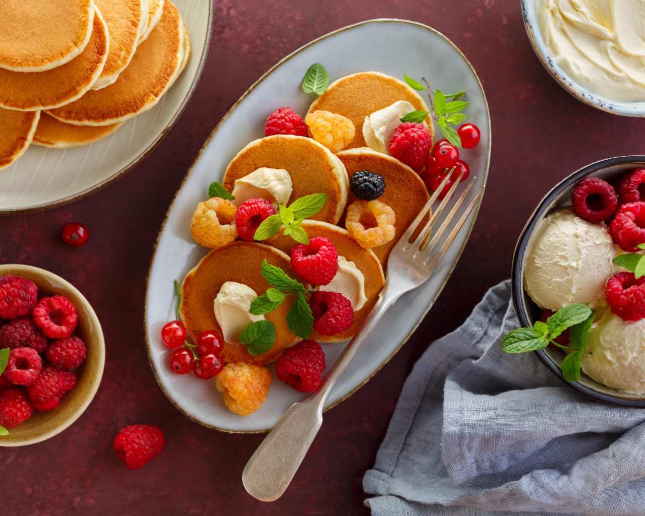 Оладьи на столе с ягодами малины и мороженым