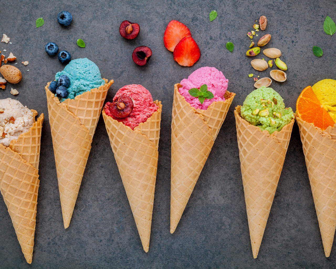 Шарики фруктового мороженого в вафельных рожках на сером фоне