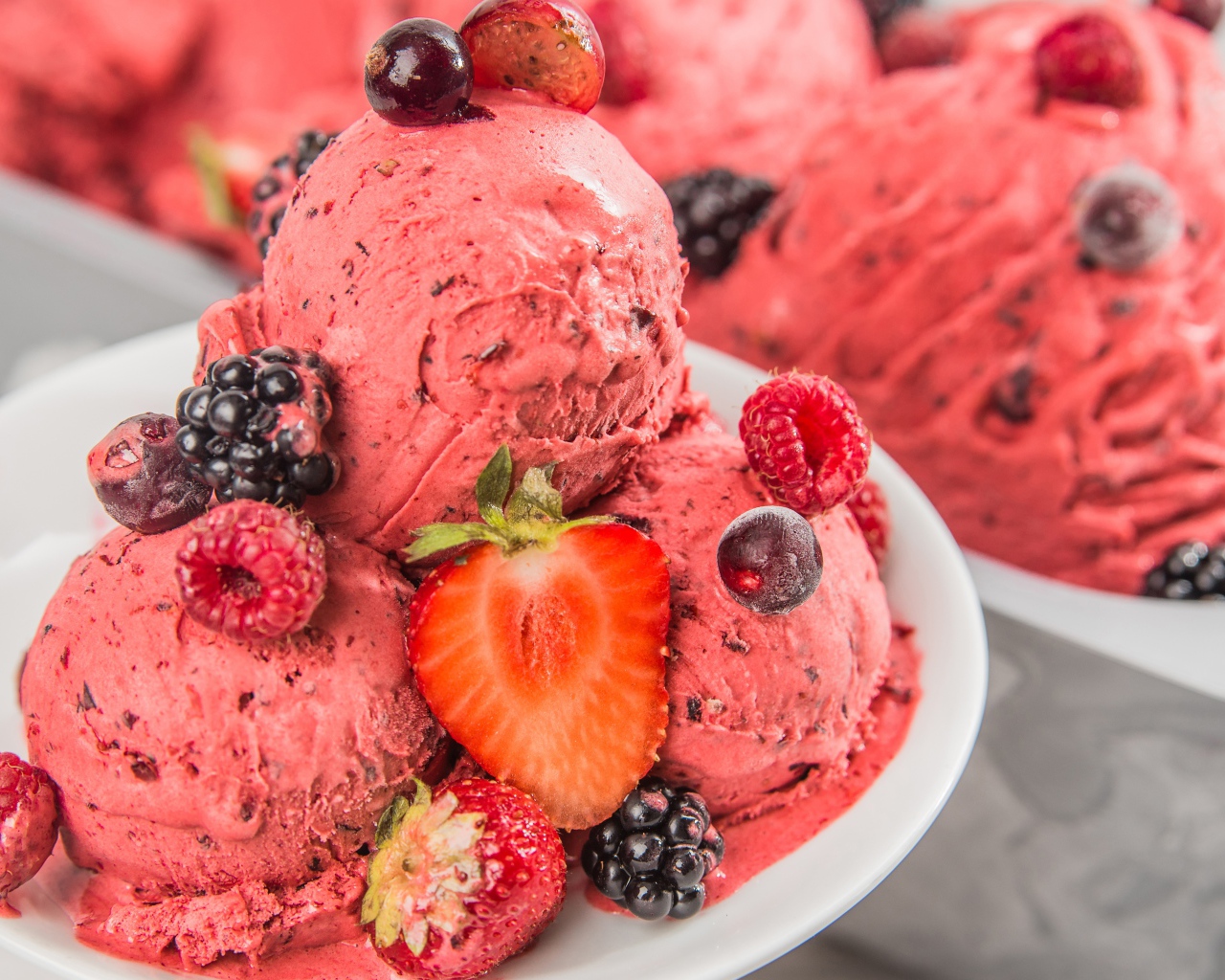Шарики фруктового мороженого на тарелке с ягодами 