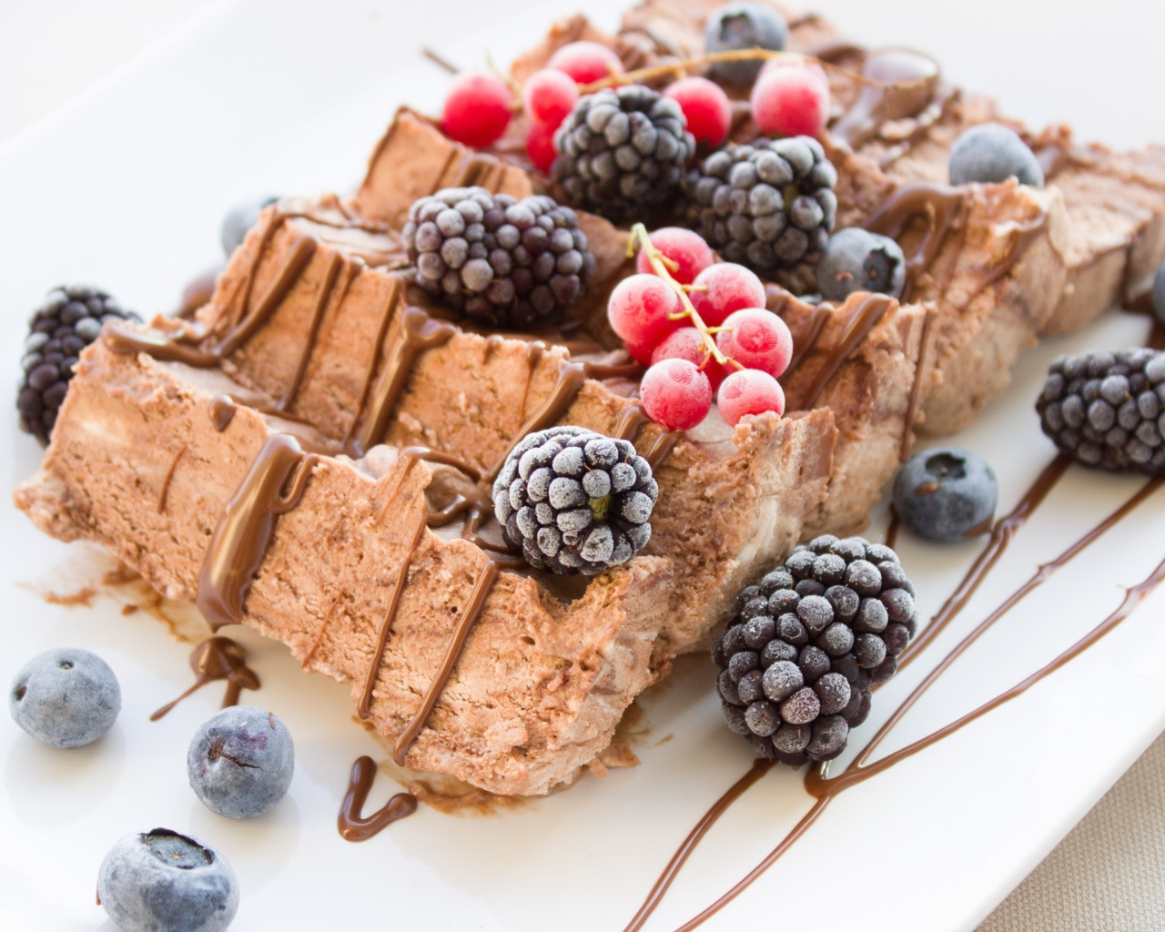 Мороженое с ягодами ежевики и красной смородины на белой тарелке 