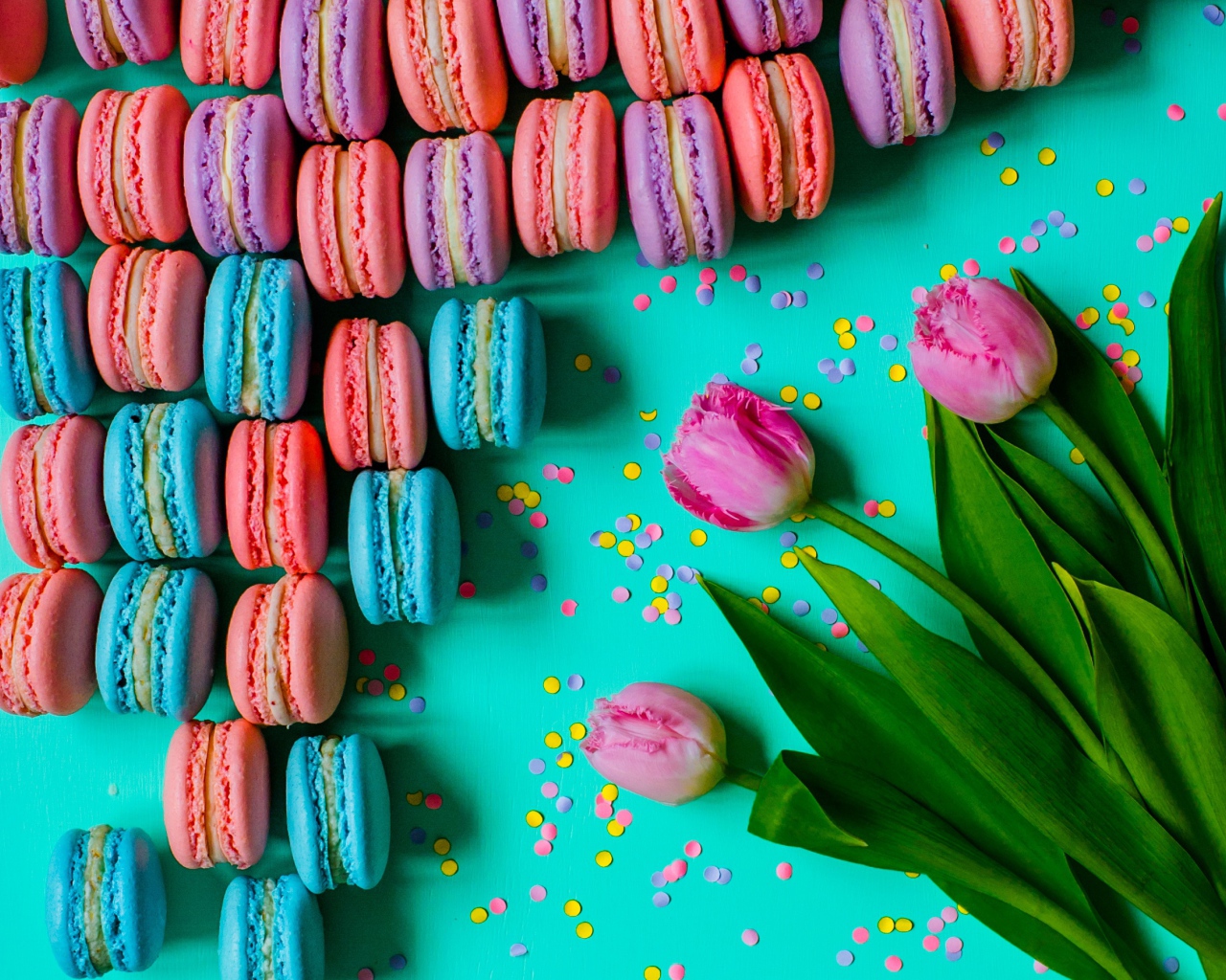 Разноцветные десерты макарун на столе с тюльпанами
