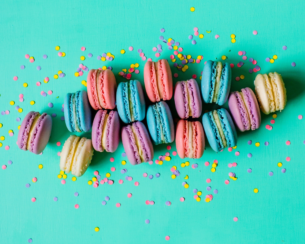 Разноцветный десерт макарун на голубом фоне с конфетти