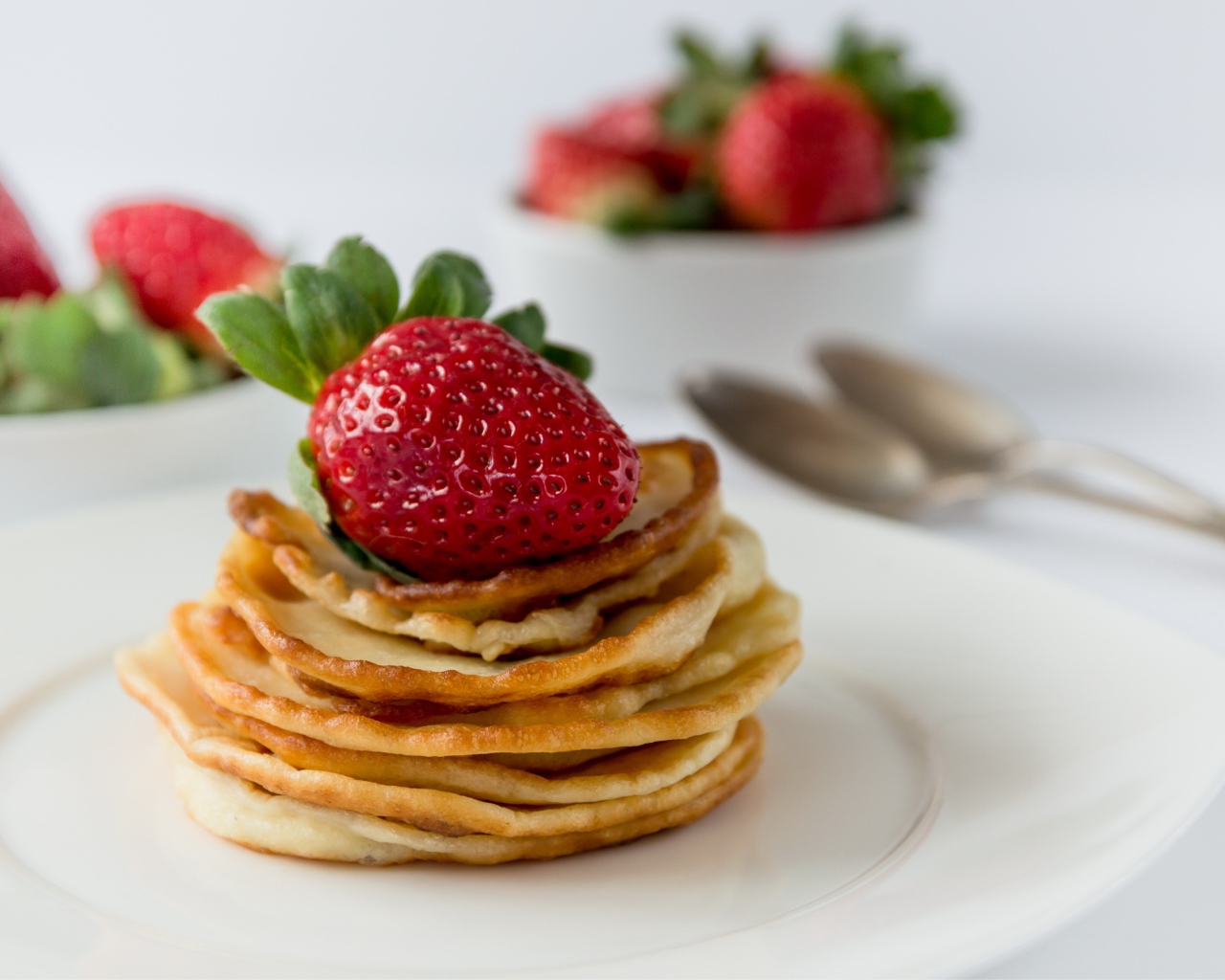 Оладьи с ягодами свежей клубники на белой тарелке 