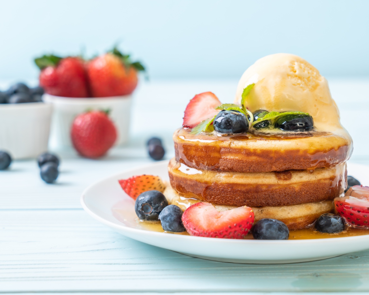 Оладья и медом, мороженым и ягодами черники и клубники на столе