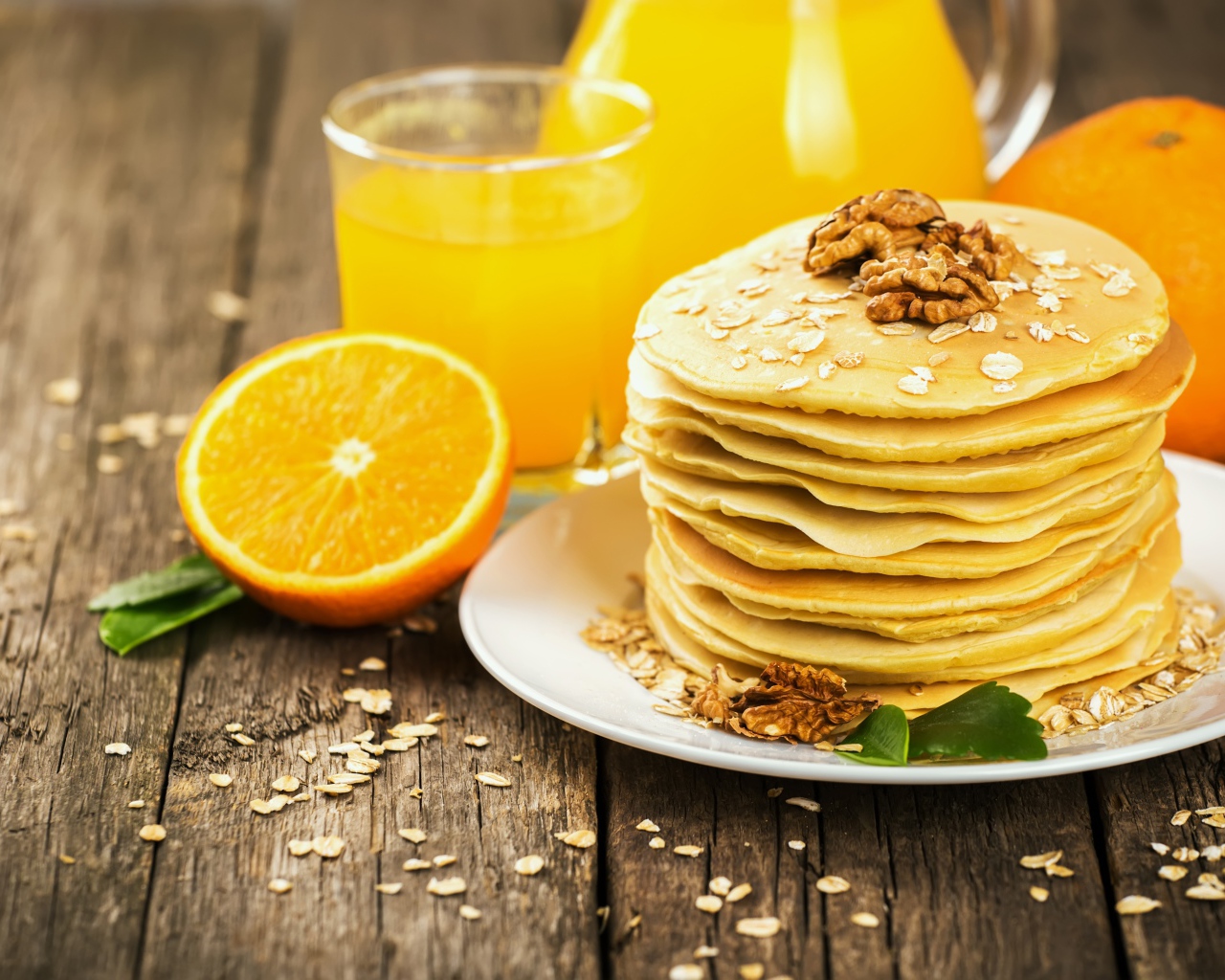 Оладьи с орехами на столе с апельсиновым соком и апельсинами