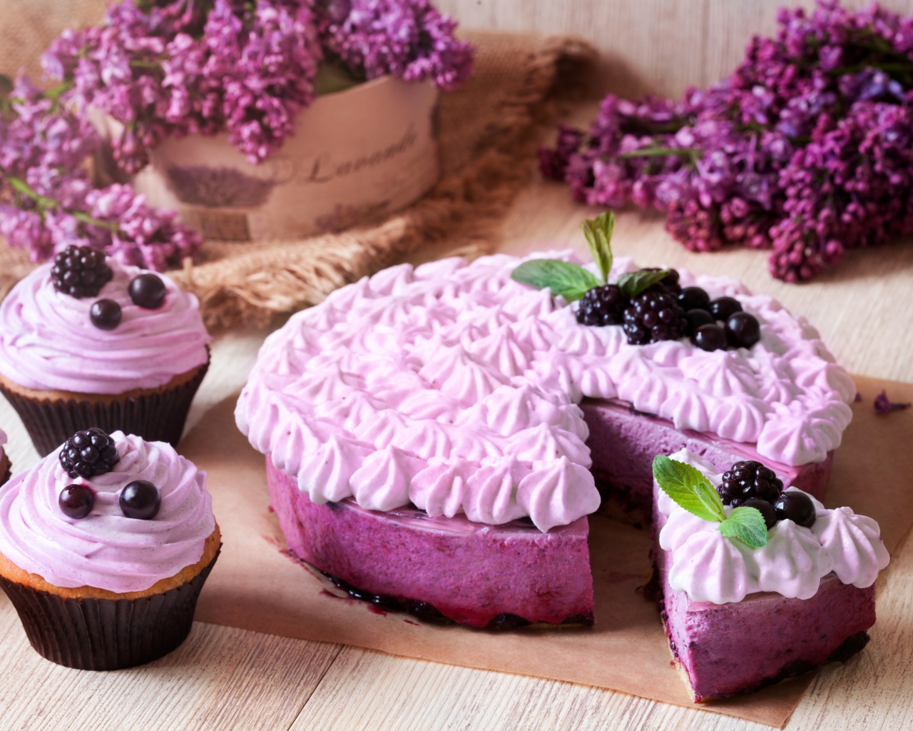 Пирог с кремом и вкусными кексами с черникой на столе с цветами сирени