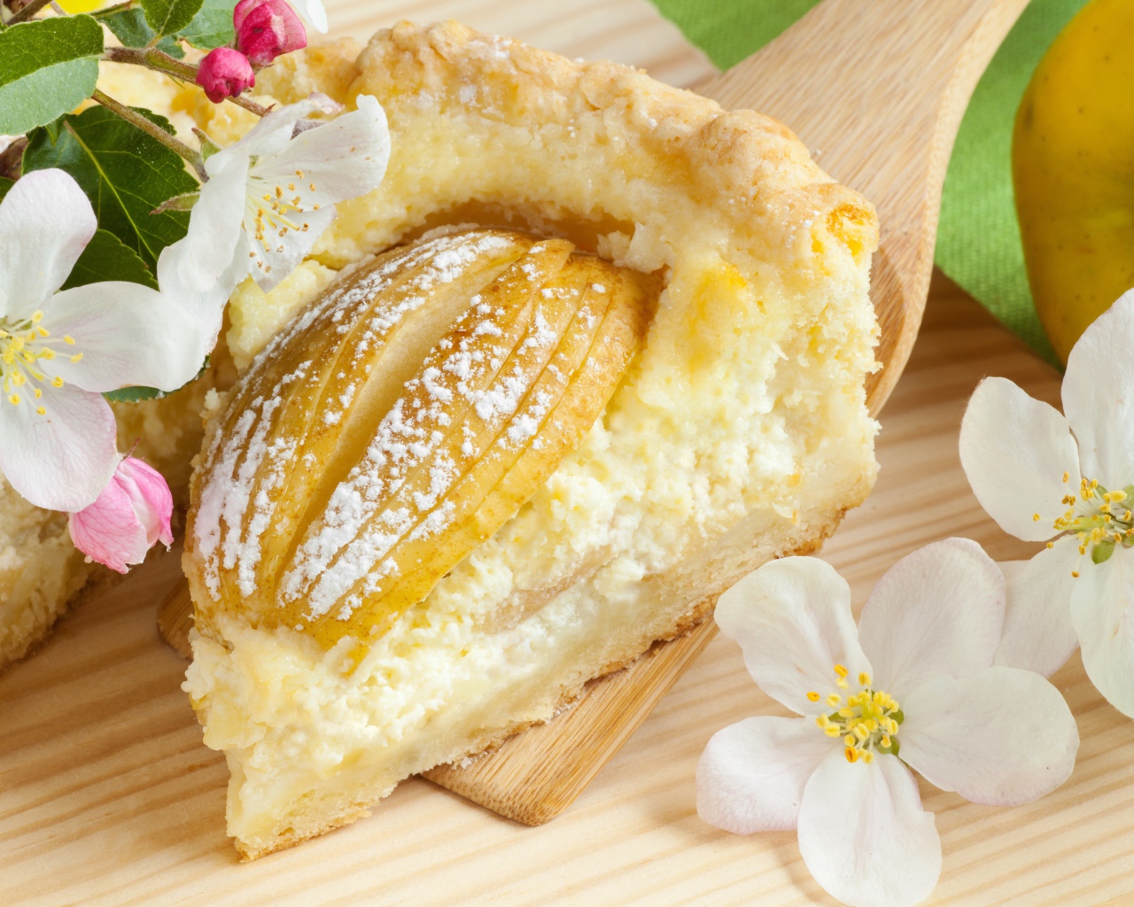 Кусок пирога с яблоками на деревянной лопатке с цветами яблони