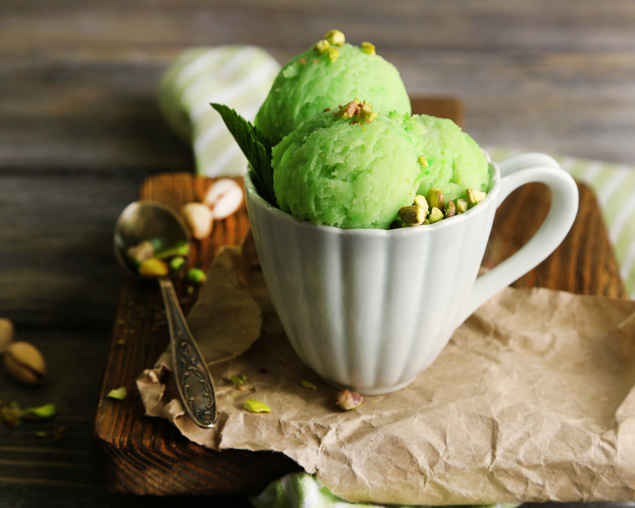 Фисташковое мороженое в белой чашке на столе