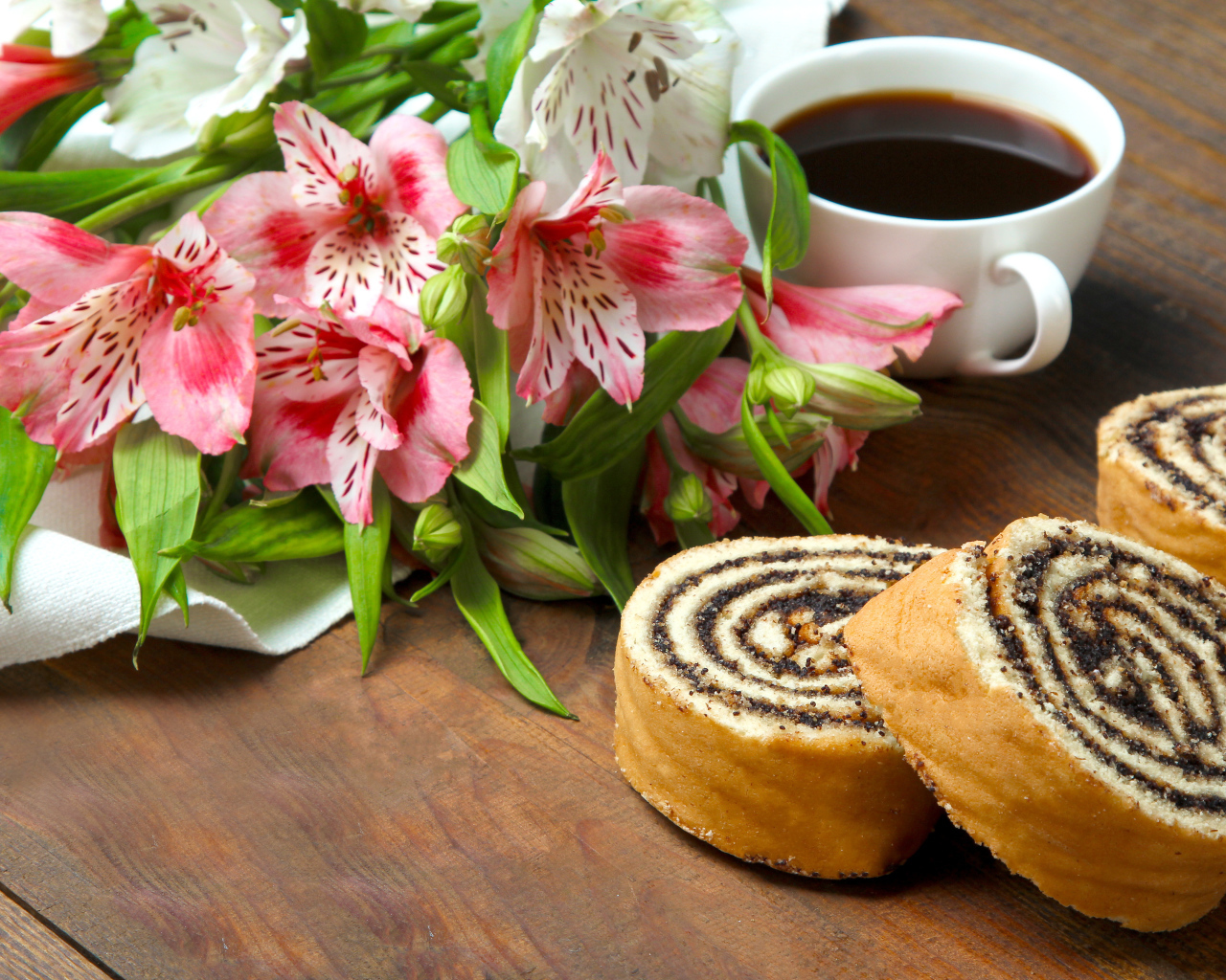 Рулет с маком на столе с цветами альстрёмерия и чашкой кофе