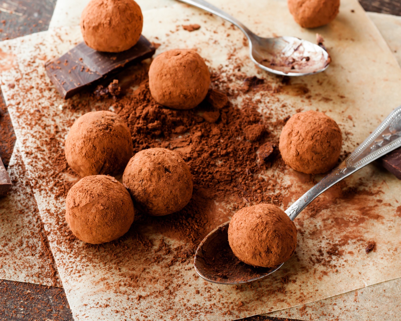Круглые шоколадные конфеты в какао на столе с ложками