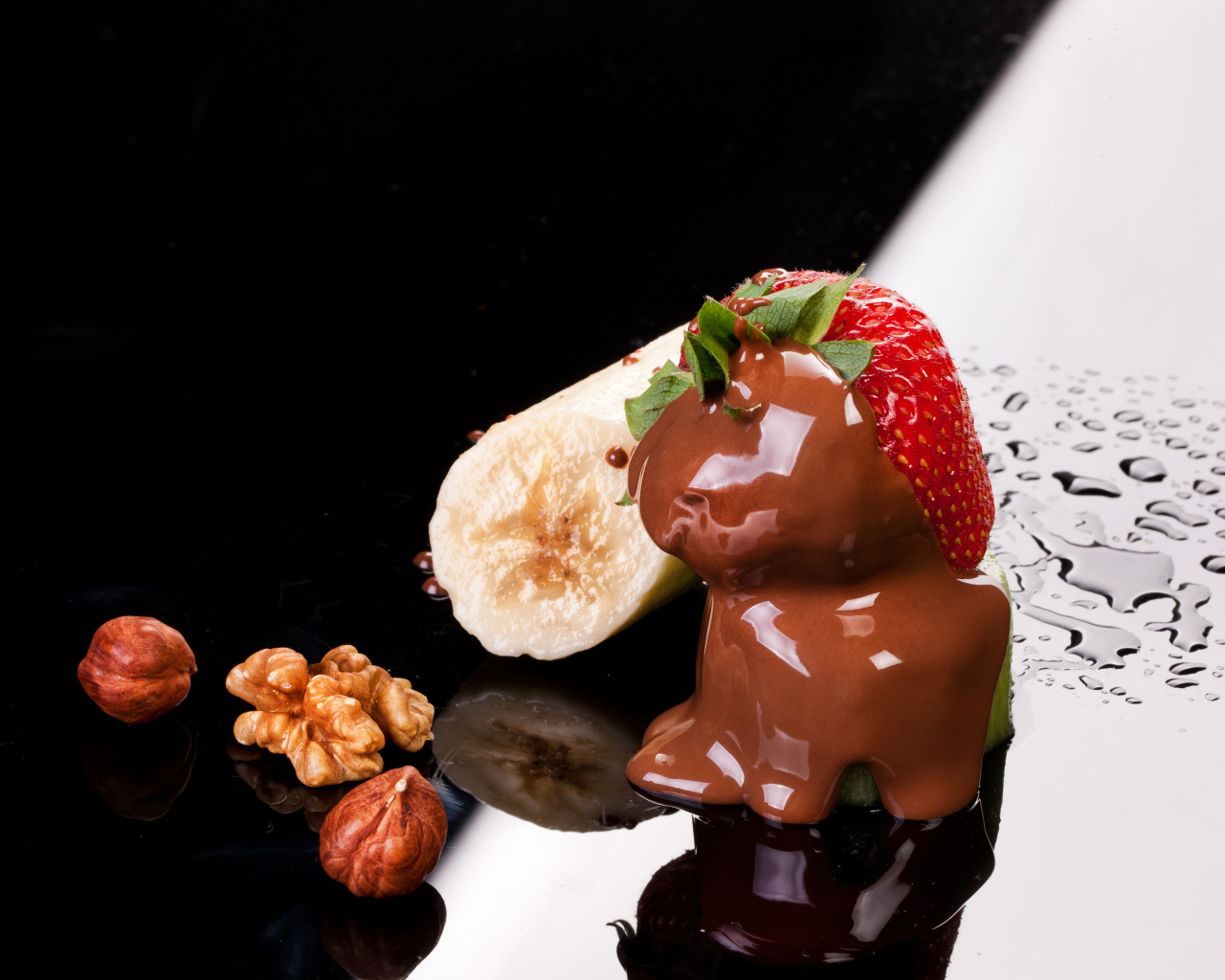 Клубника в шоколаде, банан и орехи на черной поверхности