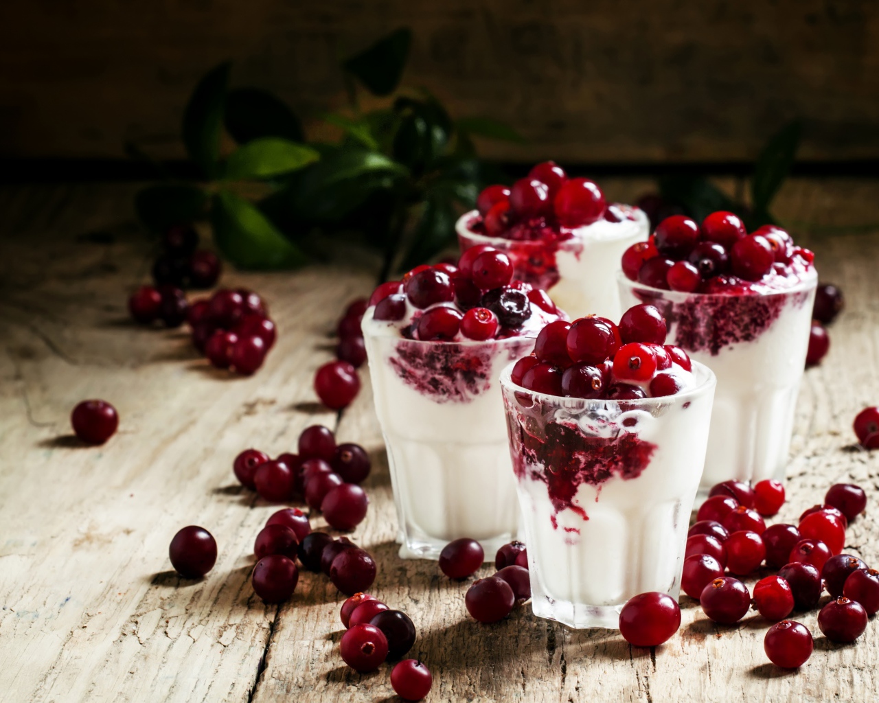 Сладкий десерт с клюквой в стеклянных стаканах