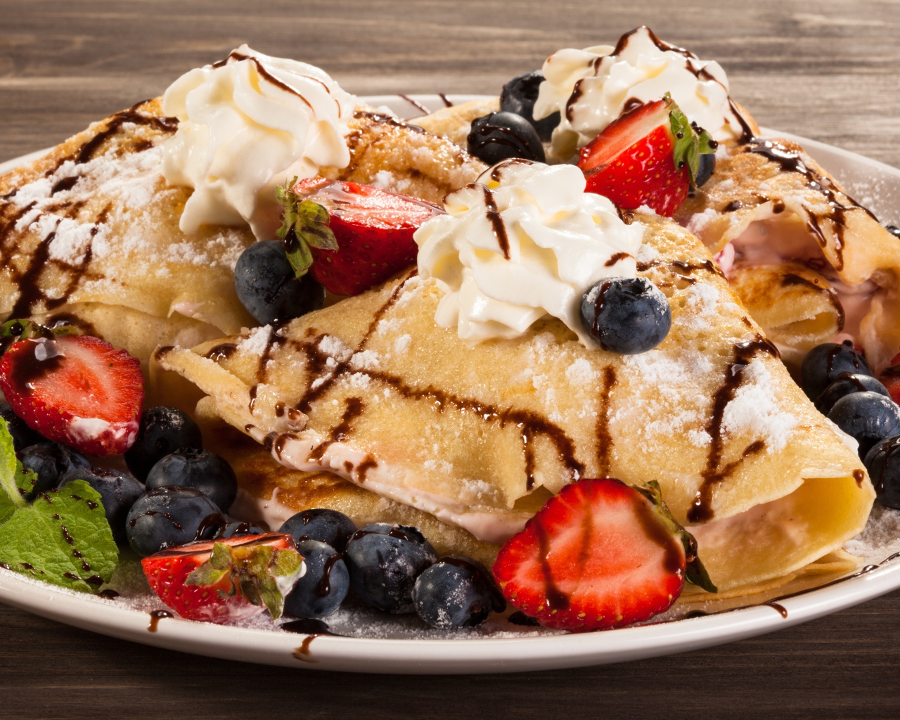 Сладкие блины с кремом, ягодами клубники и черники