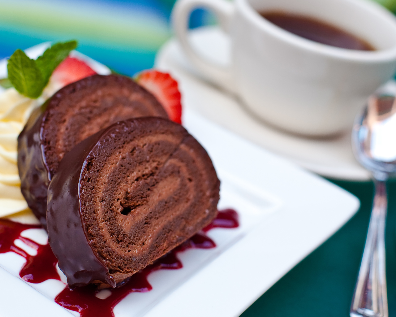 Сладкий рулет с клубничным джемом и чашкой чая на столе