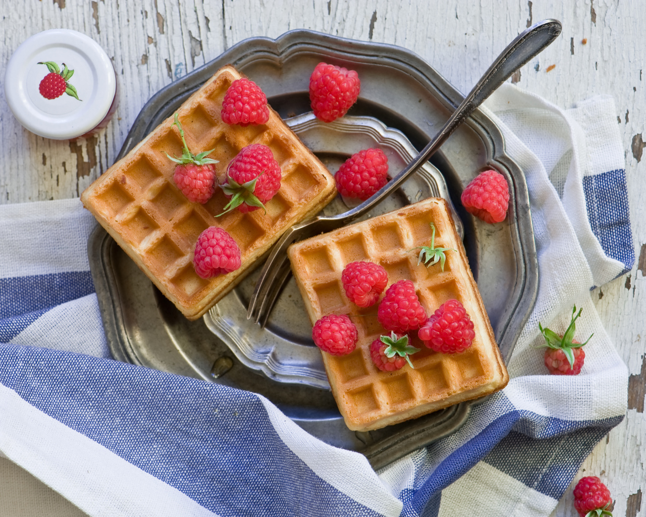 Сладкие вафли с ягодами малины на столе 