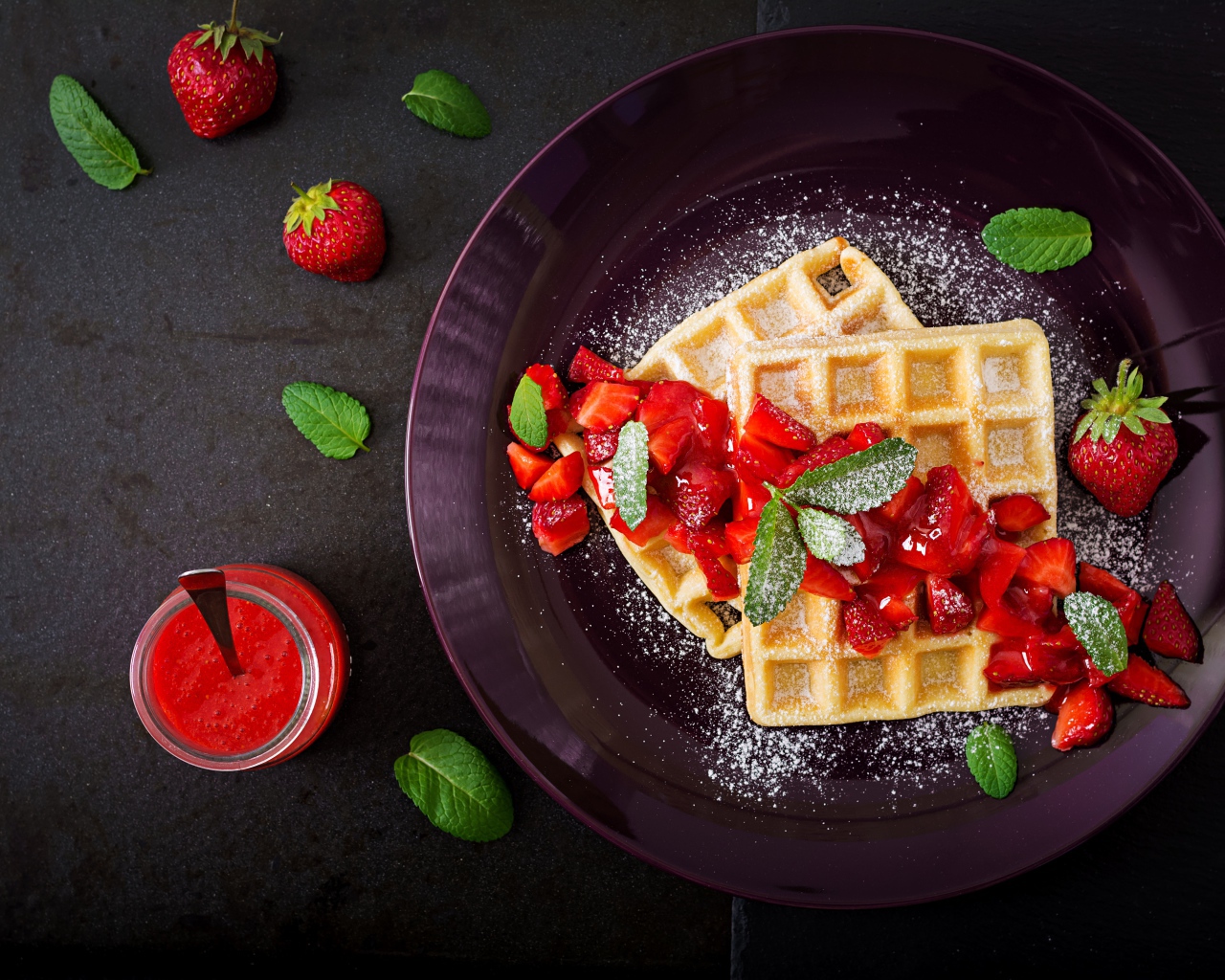 Сладкие вафли с клубникой и сахарной пудрой на тарелке 