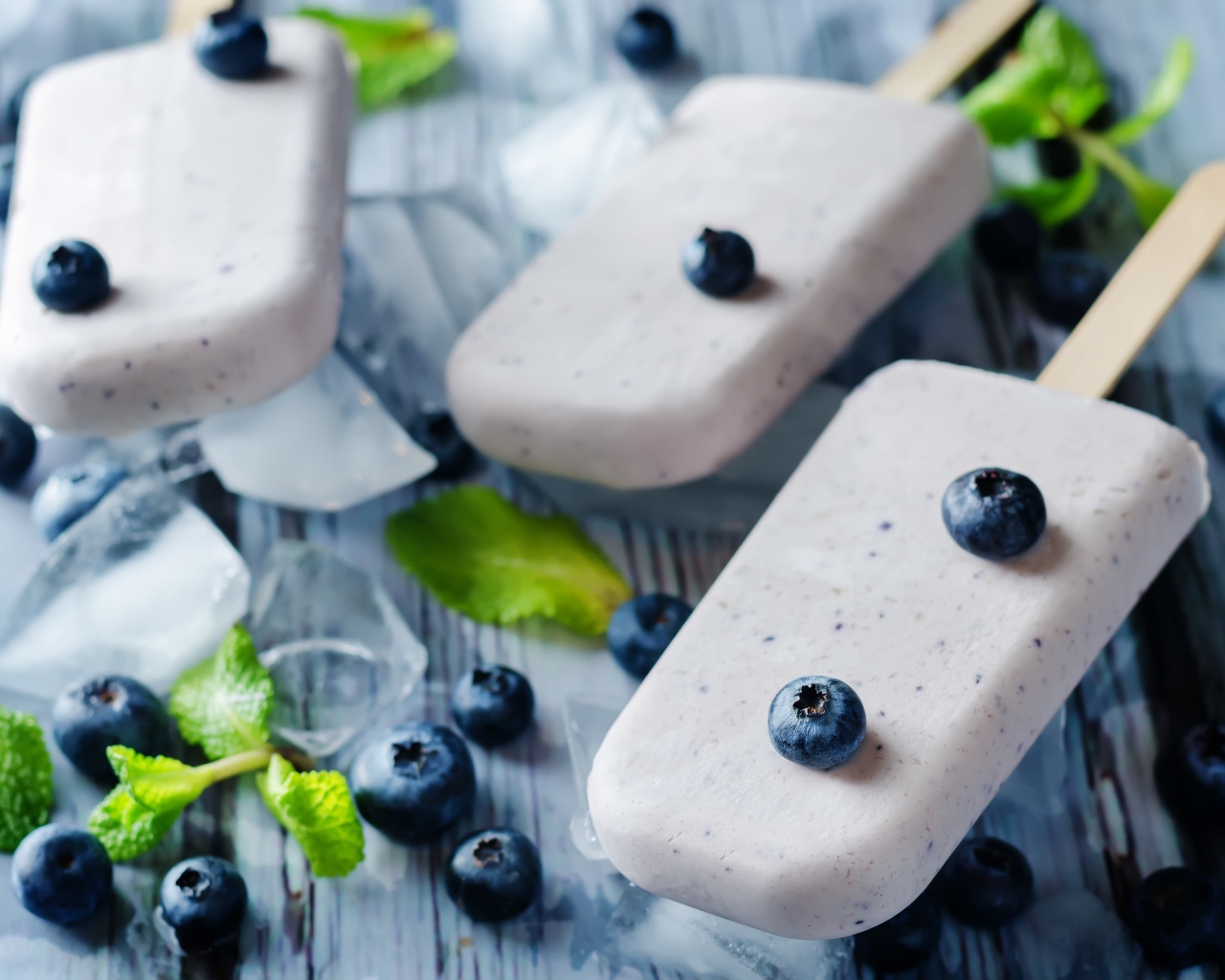 Вкусное мороженое с ягодами черники на столе с кусочками льда