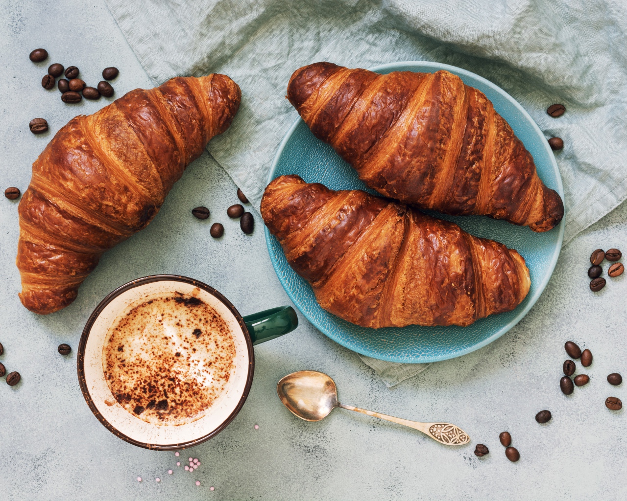 Три круассана на столе с чашкой кофе