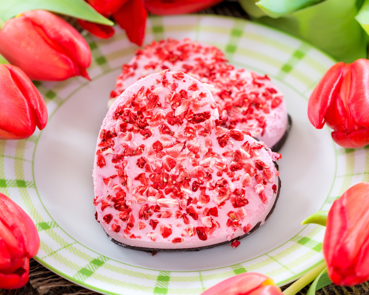 Два печенья в форме сердца на тарелке с тюльпанами 