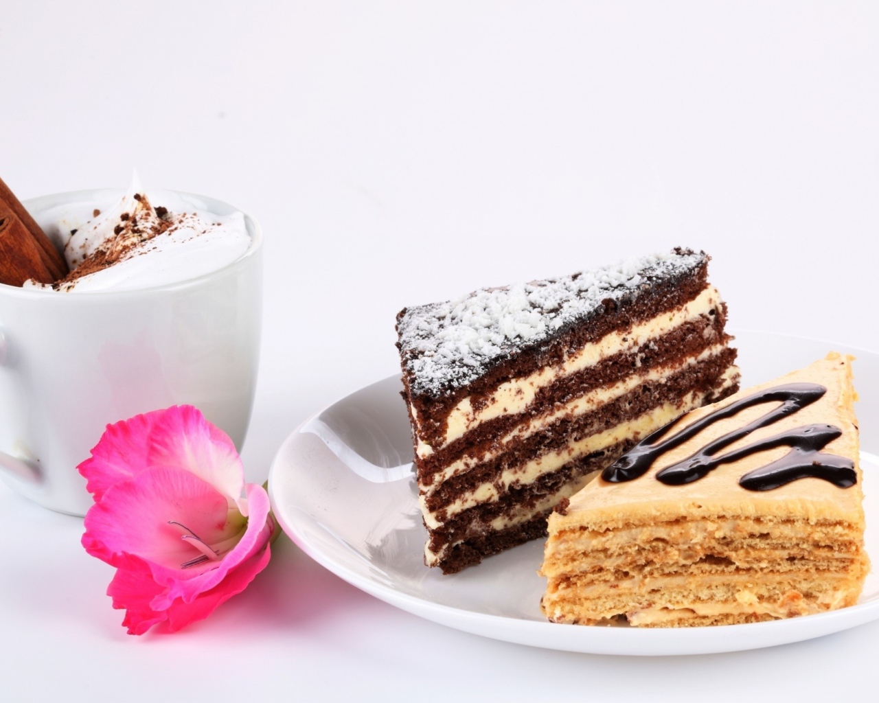 Два куска торта на столе с чашкой кофе и розовым цветком