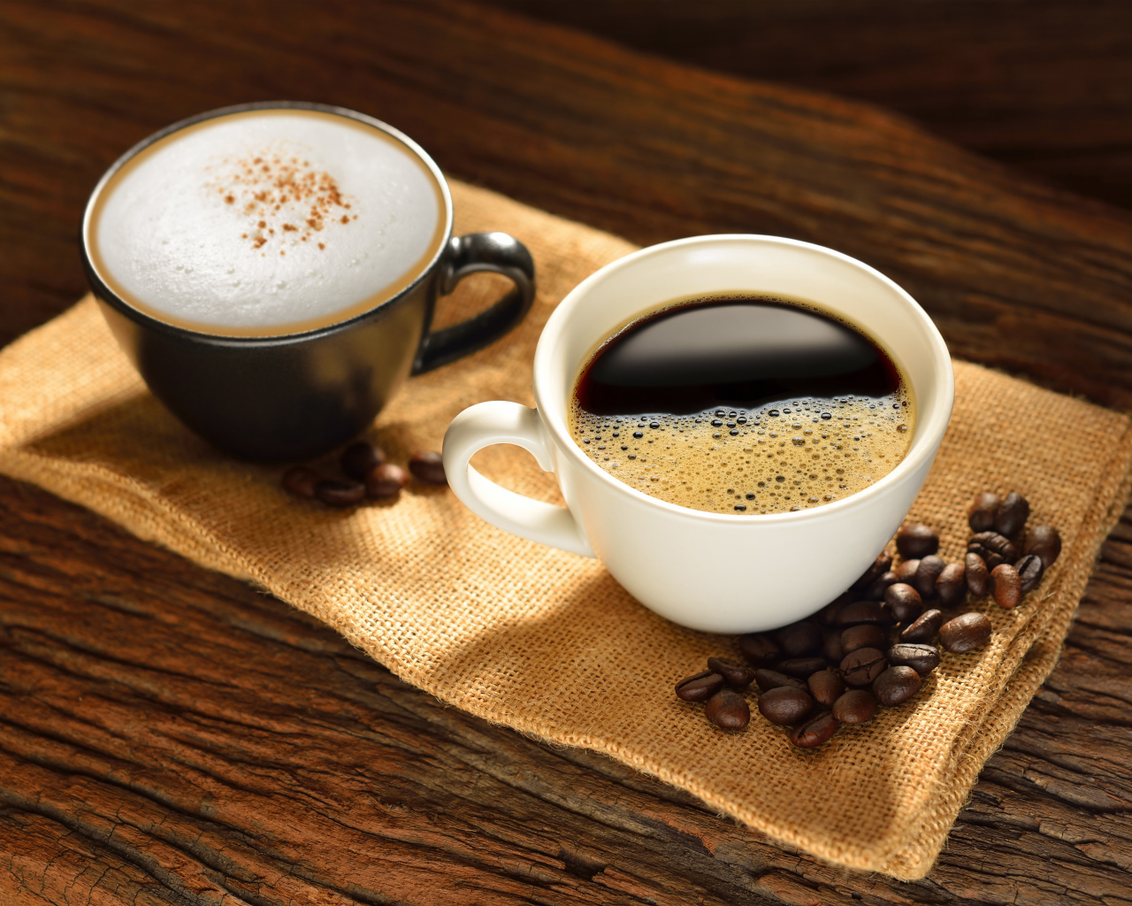Чашка кофе и чашка капучино на столе с кофейными зернами