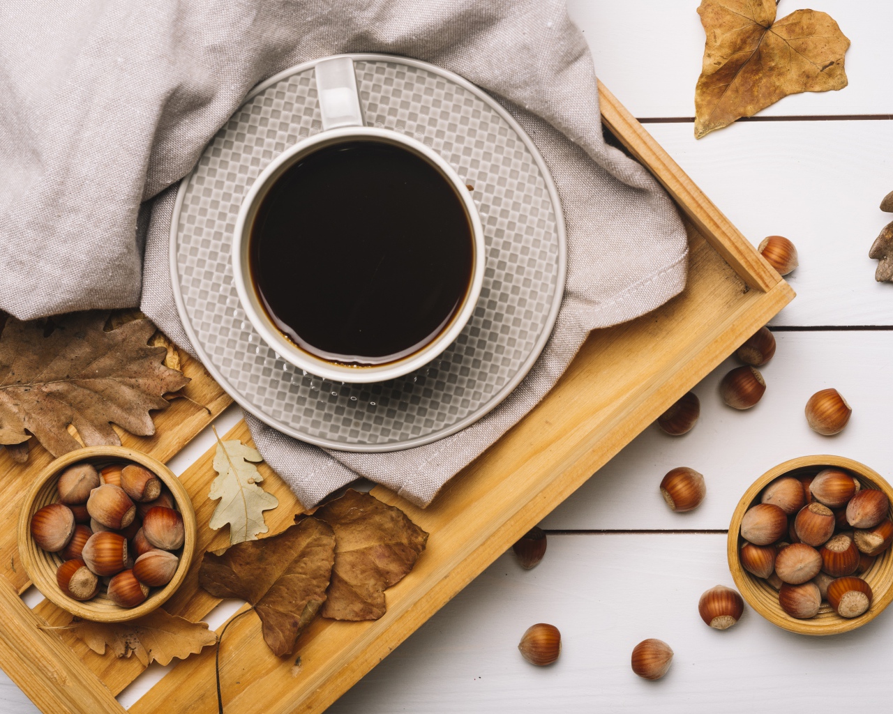 Чашка кофе на столе с лесными орехами и желтыми листьями