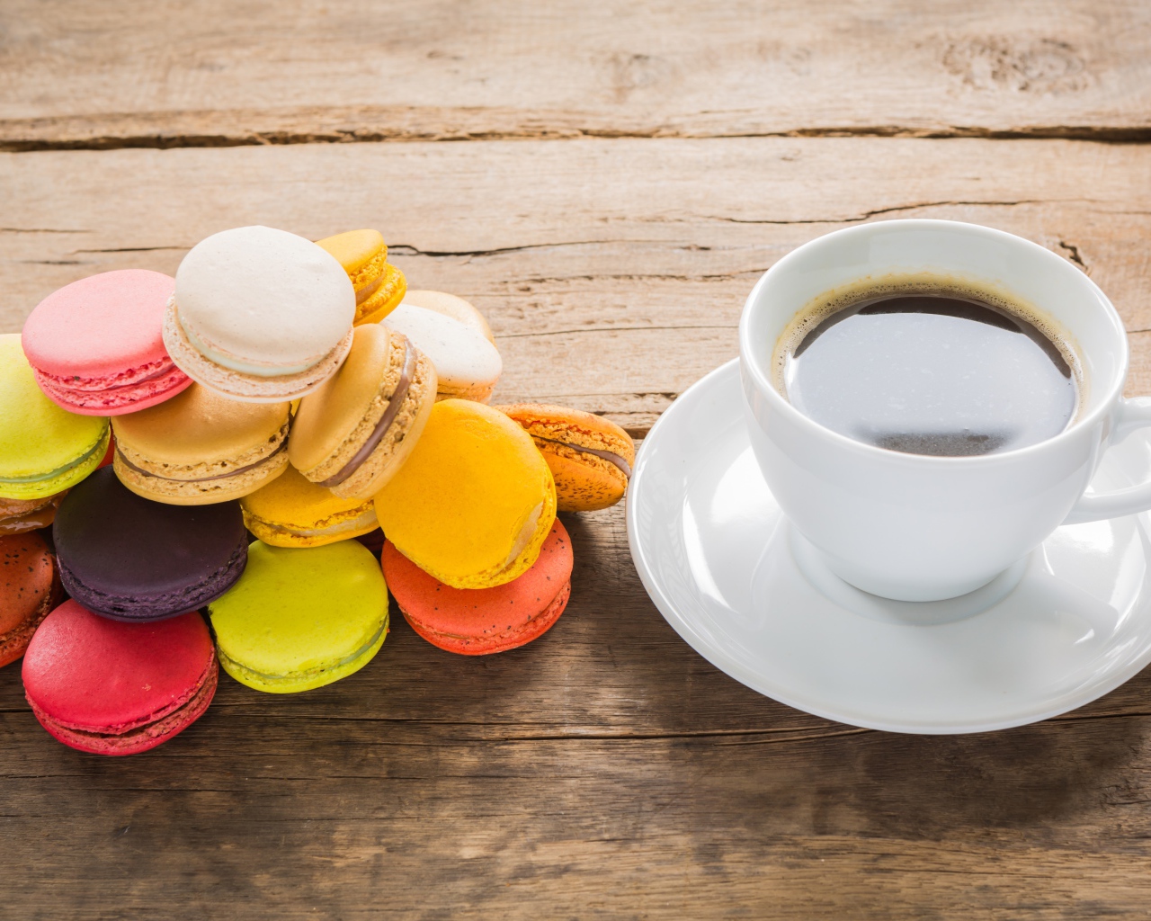 Чашка кофе на столе с разноцветными макарунами