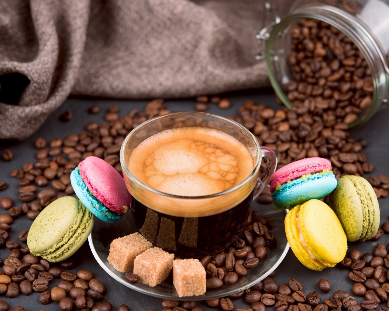 Чашка кофе с кофейными зернами, кубиками сахара и десертом макарон