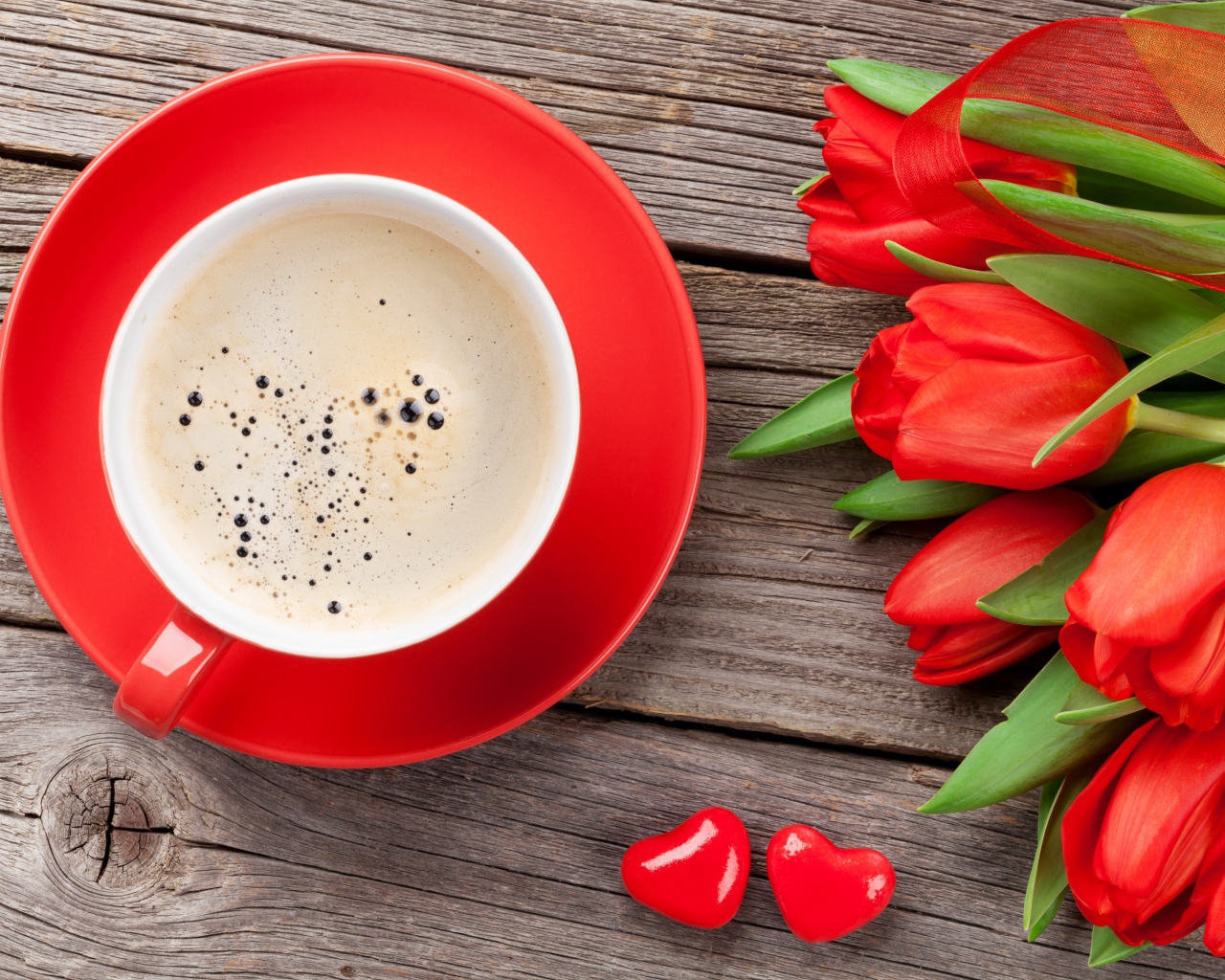 Чашка кофе с красными тюльпанами на деревянном столе 