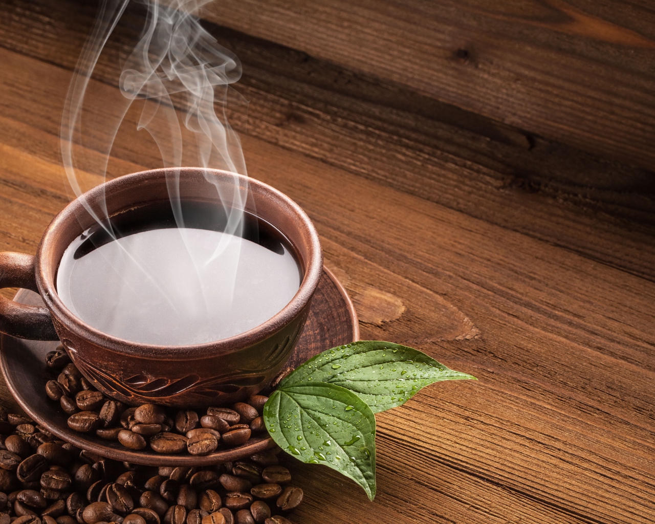 Чашка горячего кофе с зернами на деревянном столе
