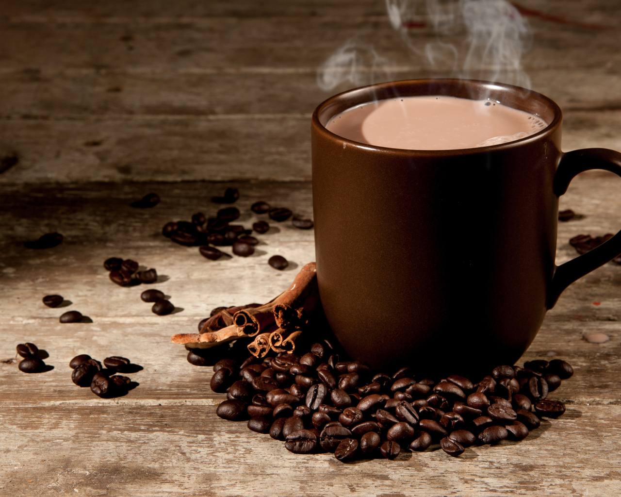 Чашка горячего кофе с молоком на столе с корицей и кофейными зернами