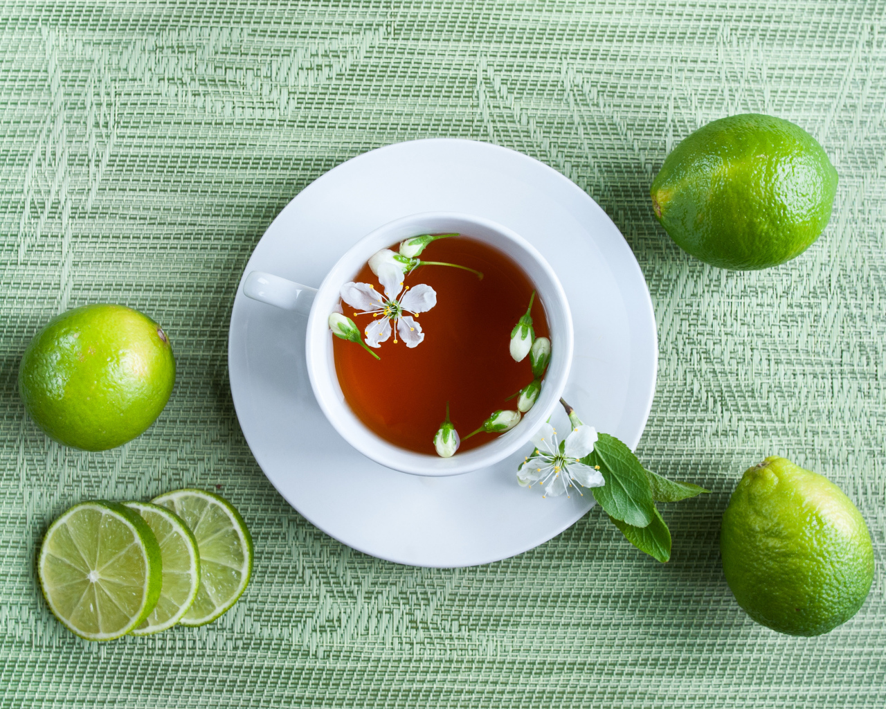 Чашка чая с зелеными лаймами на столе