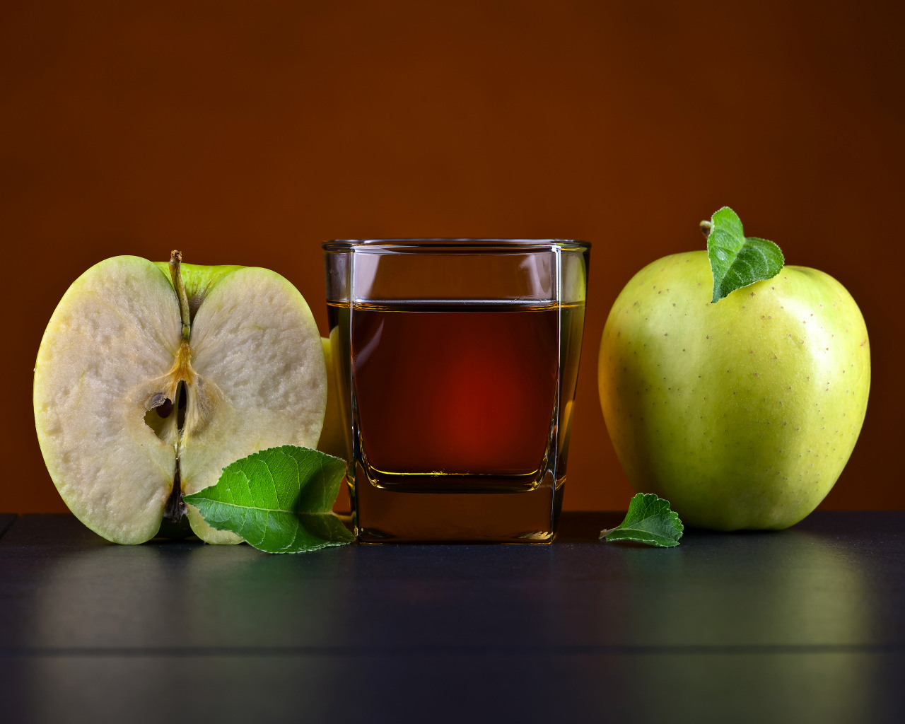 Стакан яблочного сока на столе с зелеными яблоками