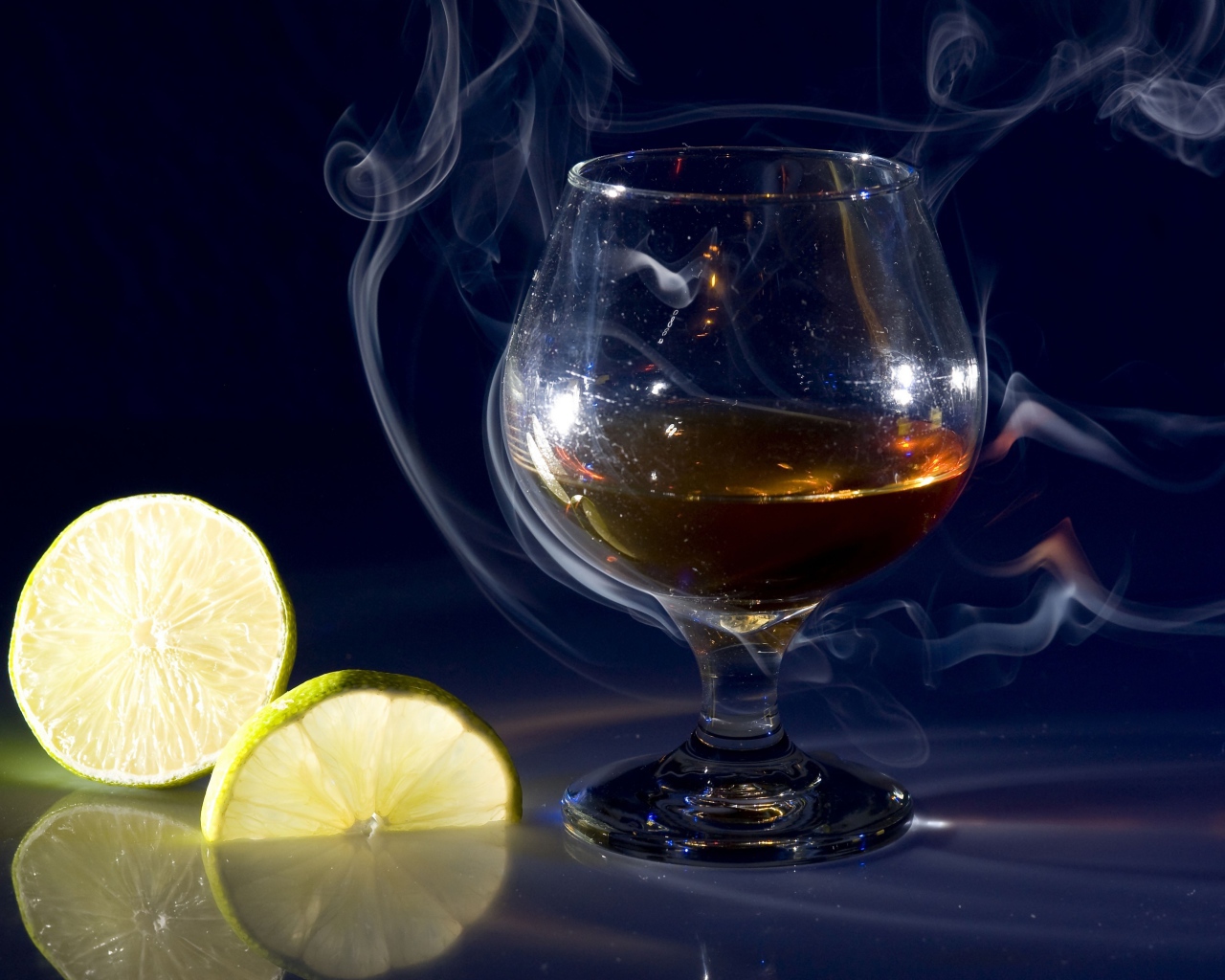 Бокал коньяка в дыму с кусочками лимона