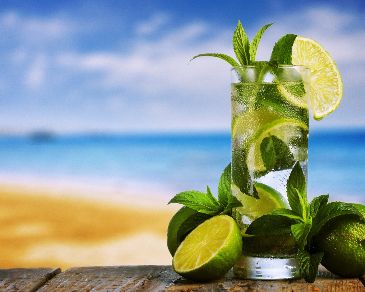 Стакан холодного мохито на столе с мятой и лаймом
