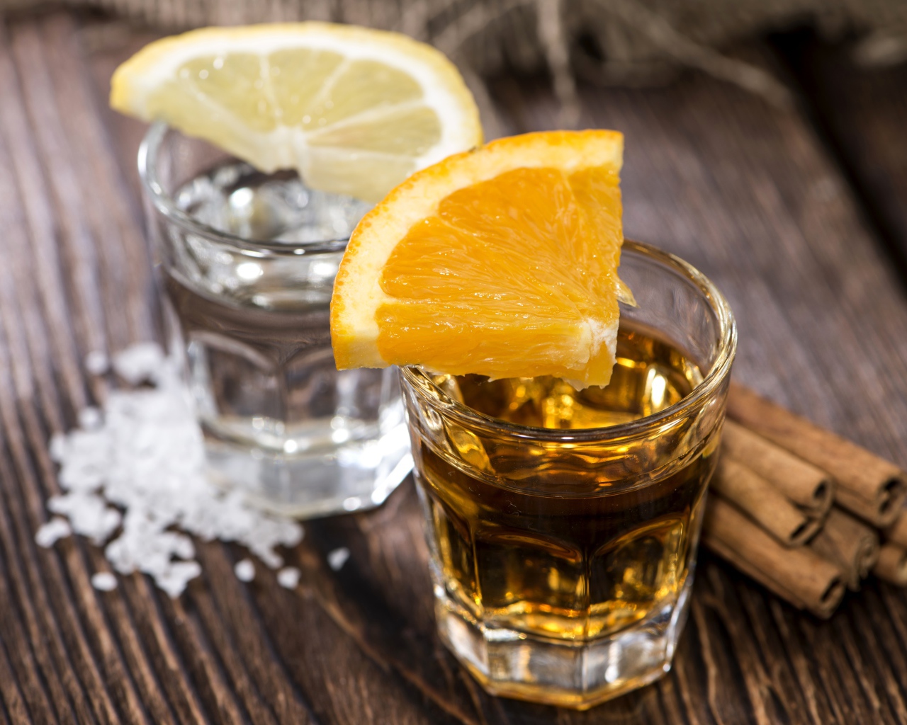 Рюмка водки и рюмка виски на столе с кусочками лимона