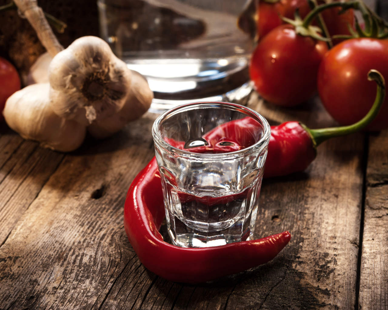 Рюмка водки на столе с красным перцем и чесноком